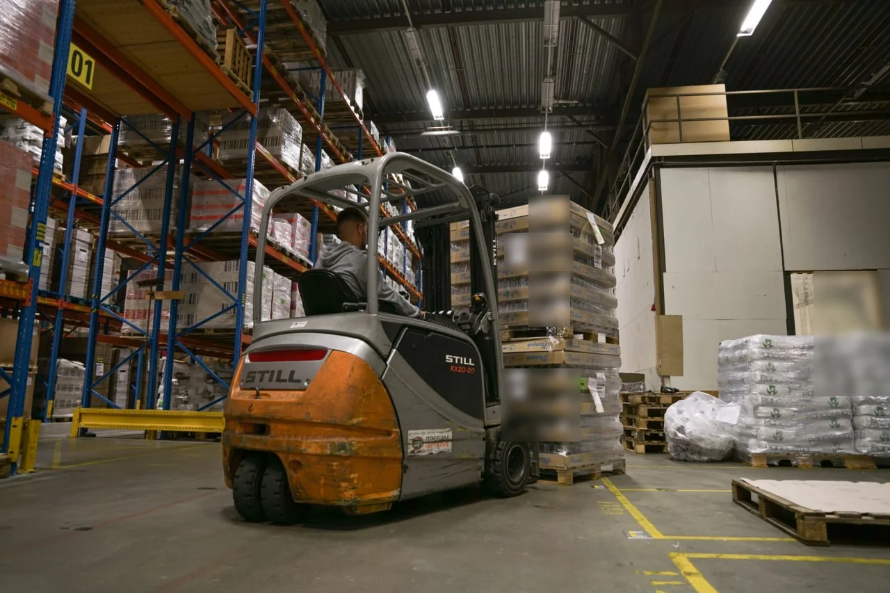 A forklift moving stacked pallets inside the warehouse.